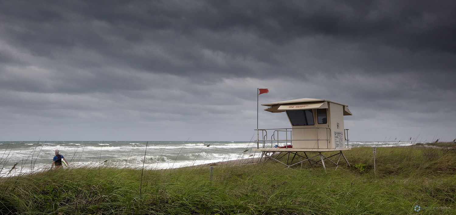 Lone surfer heading out to stormy rough surf. Jupiter, Florida, USA